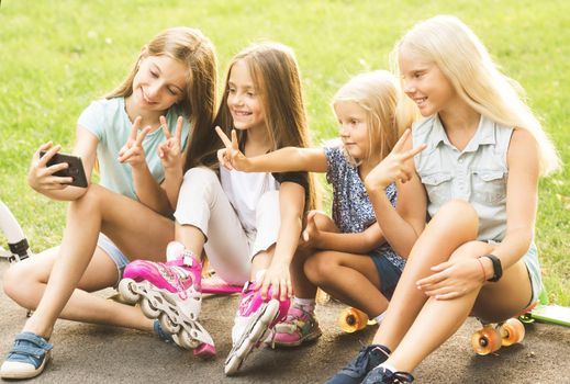 Teenage girls making selfie outdoors. Happy friends in the park on a sunny day. Happy friendship concept