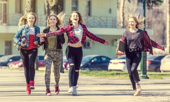Attractive smiling girls walking down the street and having fun. Happy teen girls having good time toghether walking in the park. Girls gping to skatepark