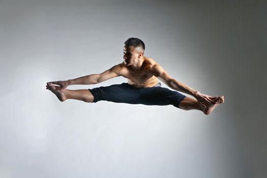 Caucasian man gymnastic leap posture on grey background