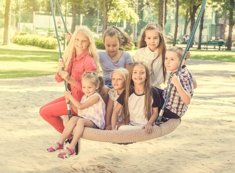 Happy smiling kids sitting on the big playgrounds swing