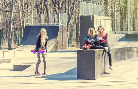 Young girl friends skateboarding at the park. Girl standing on a longboard and laughing