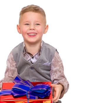 A happy little boy holds a beautifully wrapped box in which lies a gift. The concept of holidays, new year, birthday. Isolated on white background.