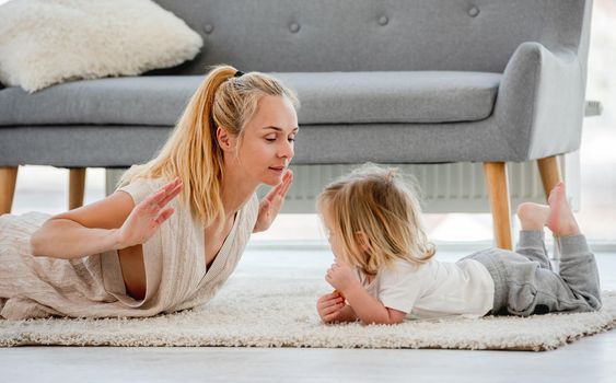 Mother with child son make exercises together laying on the floor at home