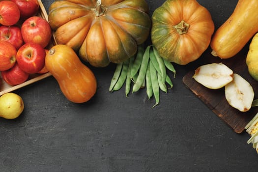 Top view of autumn vegetable composition with pumpkins and apples on black background