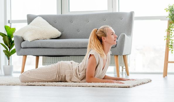 Beautiful attractive blond girl lies in yoga pose on the floor during morning workout