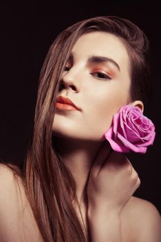 close-up portrait of beautiful brunette woman with pink rose