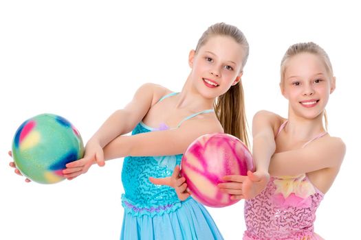 Two cheerful little girls gymnasts in competitions, perform exercises with the ball. The concept of children's sports, fitness, healthy lifestyle. Isolated on white background.