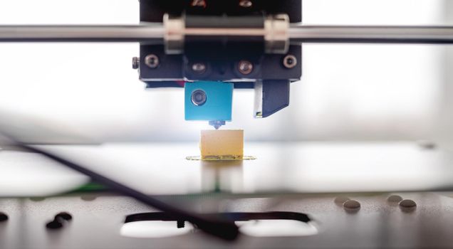 3D printer developing plastic yellow product. Closeup view of printing process