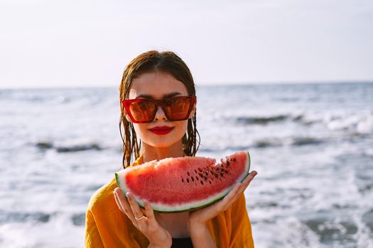 woman on the beach near the ocean eating watermelon. High quality photo