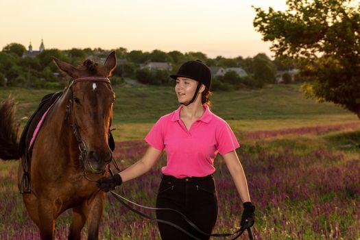 Beautiful young girl smile at her horse dressing uniform competition: outdoors portrait on sunset. Taking care of animals, love and friendship concept.
