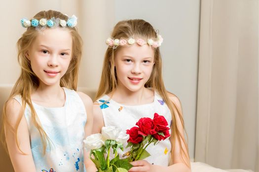 Two beautiful little girls with flowers in the studio. The concept of happy people, children.