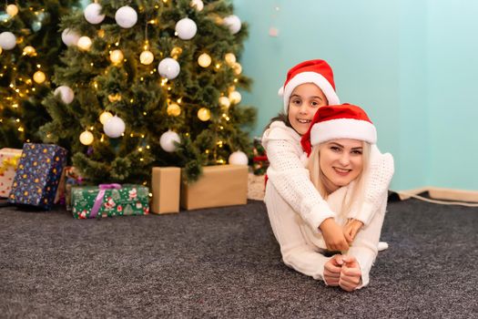 A young and happy mother and daughter in Christmas hats