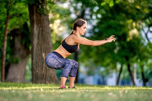 Sport girl doing yoga workout at nature in summertime and standing in squat pose. Young woman exercising and stretching outdoors in the morning