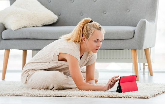 Young blond girl watching yoga class in tablet online during covid pandemy