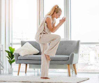 Beautiful girl in beige knitted outfit making morning yoga workout at home