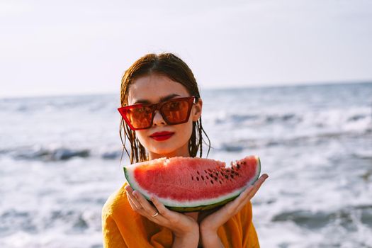 woman on the beach near the ocean eating watermelon. High quality photo