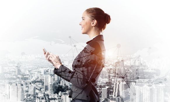 Young businesswoman using mobile phone. Double exposure concept with modern downtown architecture and beautiful woman in business suit. Digital technology in property management and development.