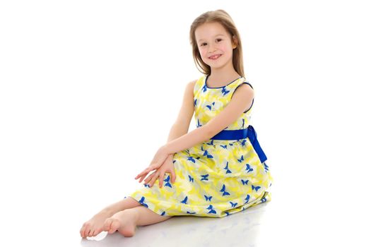 Beautiful little girl is sitting on the floor in the studio. The concept of a happy childhood, beauty and fashion. Isolated on white background.