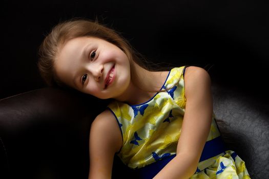 Beautiful little girl, studio portrait on a black background. The concept of a happy childhood, style and fashion.