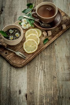 Freshly brewed jasmine tea with lemon in brown cups sitting on cutting board, copyspace left