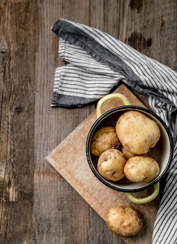 Delicious young potatoes sitting on a cutting board, blue and white napkin, topview