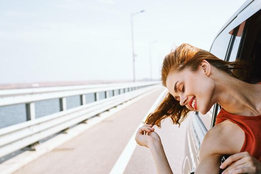 cheerful woman peeking out of the car window trip road travel. High quality photo
