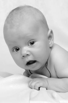 A charming baby lies on the blanket and looks into the camera. The concept of a happy childhood, the birth and upbringing of a child.