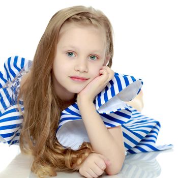 Adorable little blond girl in very short summer striped dress.She lies on the floor and looks directly into the camera.Isolated on white background.