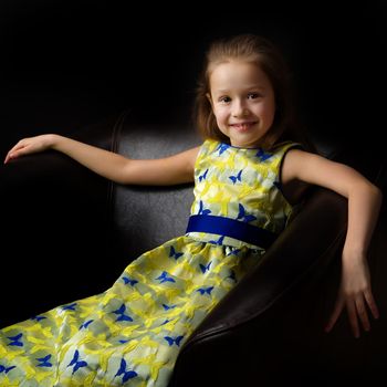 Beautiful little girl, studio portrait on a black background. The concept of a happy childhood, style and fashion.