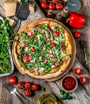 Pizza with ham, arugula and cherry tomatoes
