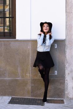 Portrait of young woman in urban background wearing casual clothes and hat