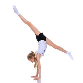 A girl gymnast performs an acrobatic element on the floor. The concept of childhood, sport, healthy lifestyle. Isolated on white background.