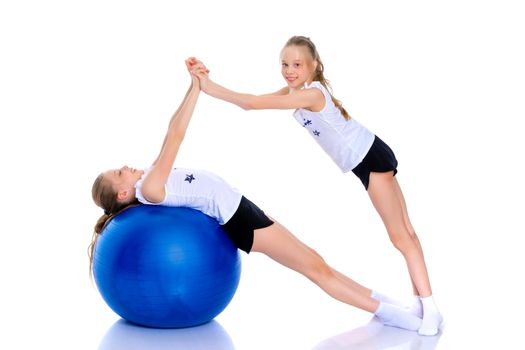 Jolly girls gymnasts perform exercises with a large ball for fitness. The concept of children's sport, a healthy lifestyle. Isolated on white background.