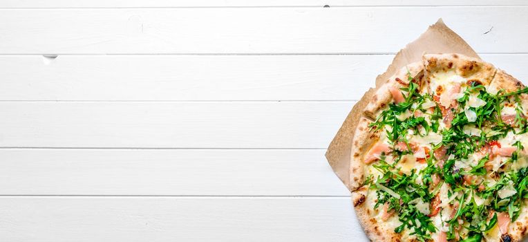Itallian homemade pizza served on white wooden background with cutlery and cherry tomatoes. Copyspace, top view