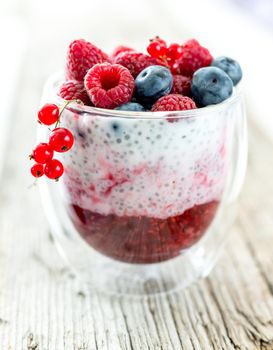 Dessert from yogurt with chia seeds, raspberries and blueberries on a old wooden background. top view