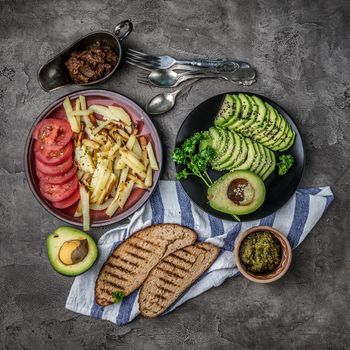 Huge plates full of fried potatoes with fresh tomatoes, cut fresh avocado, toasted bread, topview