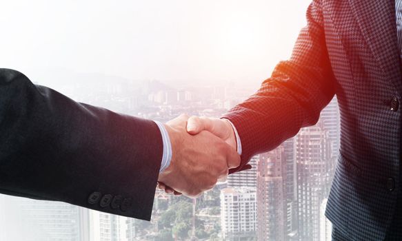 Close-up of the handshake of businessmen. Against the backdrop of the cityscape