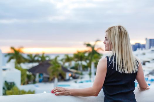 Young girl standing on the balcony overlooking the sea.
