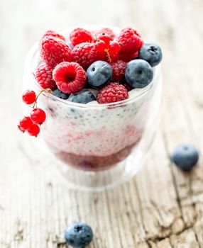 Dessert from yogurt with chia seeds, raspberries and blueberries on a old wooden background. top view
