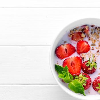 Huge bowl of granola with strawberries and mint leaves, additional textspace left on side, topview