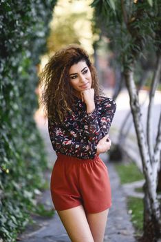 Beautiful young arabic woman with black curly hairstyle. Arab girl wearing casual clothes in the street.