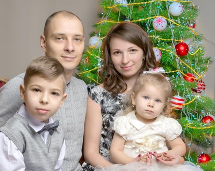 Happy young family with children at Christmas near a Christmas tree and a fireplace. The concept of holidays, winter, Christmas, Happy childhood, the harmonious development of children in the family.