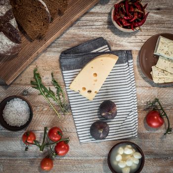 bread with cheeses and grapes and wineglass on wooden background