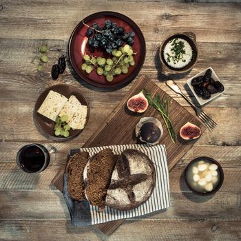 bread with cheeses and grapes and wineglass on wooden background