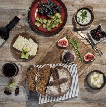 bread with cheeses and grapes and wineglass on wooden background