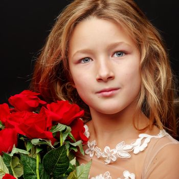 Beautiful little girl with a bouquet of flowers on a black background. The concept of a happy childhood, beauty and fashion.
