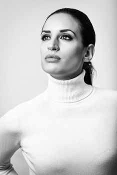 Young brunette woman wearing white poloneck. Attractive girl, model of fashion in black and white. Studio shot on white background.