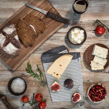 bread with cheeses and grapes and wineglass on wooden background