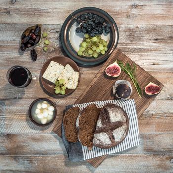 bread with cheeses and grapes and wineglass on wooden background