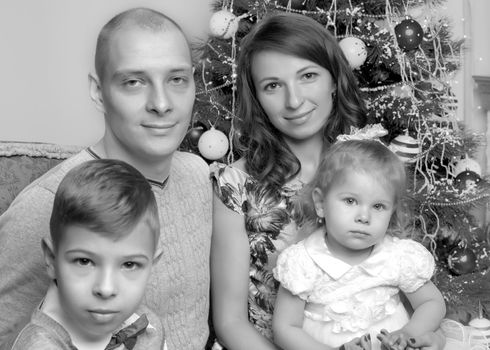 Happy young family with children at Christmas near a Christmas tree and a fireplace. The concept of holidays, winter, Christmas, Happy childhood, the harmonious development of children in the family.